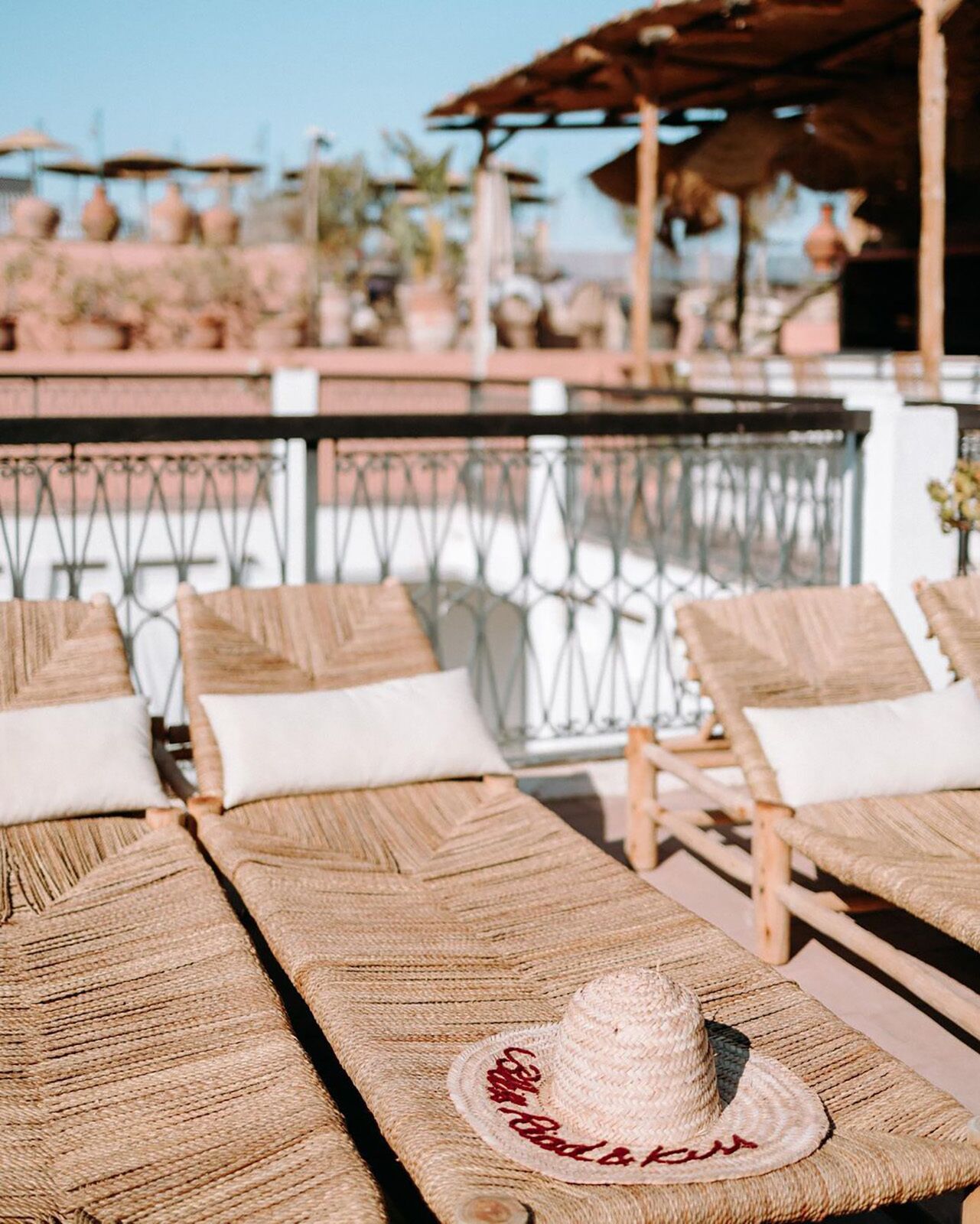 A beachside lounge area with wicker furniture and a straw hat on a table.