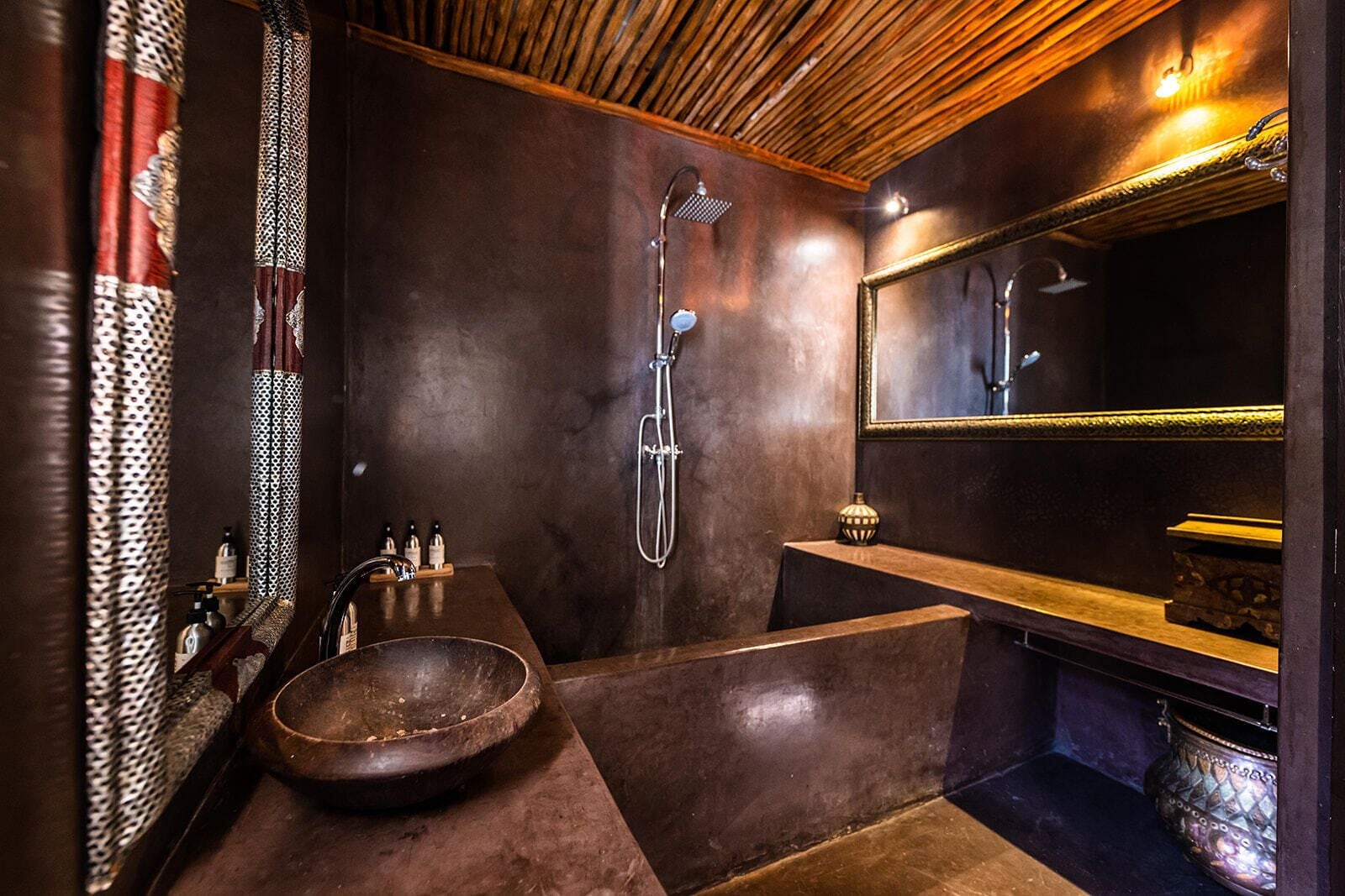 Un baño moderno con un espejo grande, un tocador de madera, una bañera independiente y una ducha con cabezal de ducha de mano.