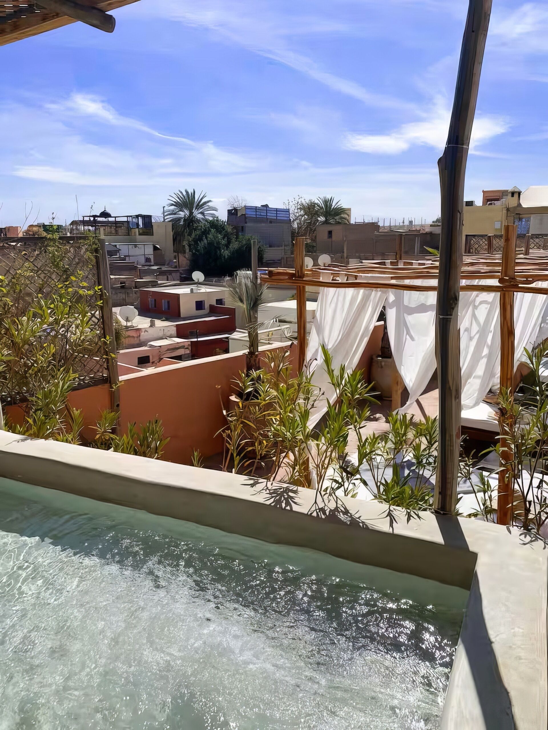 A rooftop pool area with a view of surrounding buildings and vegetation.