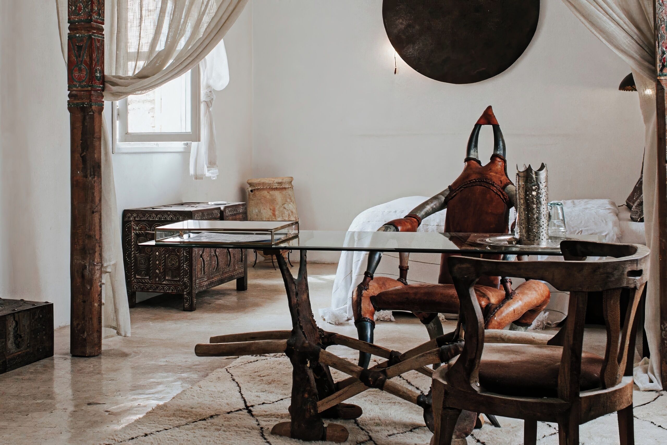 Une pièce rustique avec une table en bois, une chaise, une grande corne décorative et une fenêtre avec des rideaux.