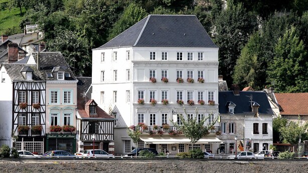 A multi-story hotel with a white facade, multiple windows, and flower boxes on the balconies. - Hôtel Restaurant Le Bellevue (La Bouille)