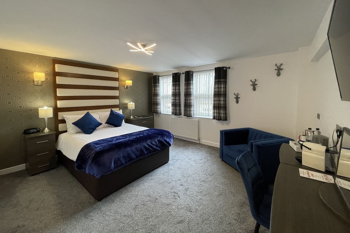 A modern bedroom with a large bed, a desk, and a chair.