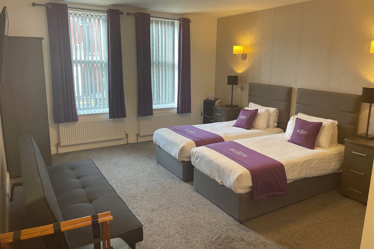 A hotel room with two beds, a desk, and a chair.
