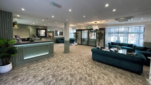 A spacious lobby with a reception desk, seating area, and a large window providing natural light. - Ruskin Hotel (Blackpool)