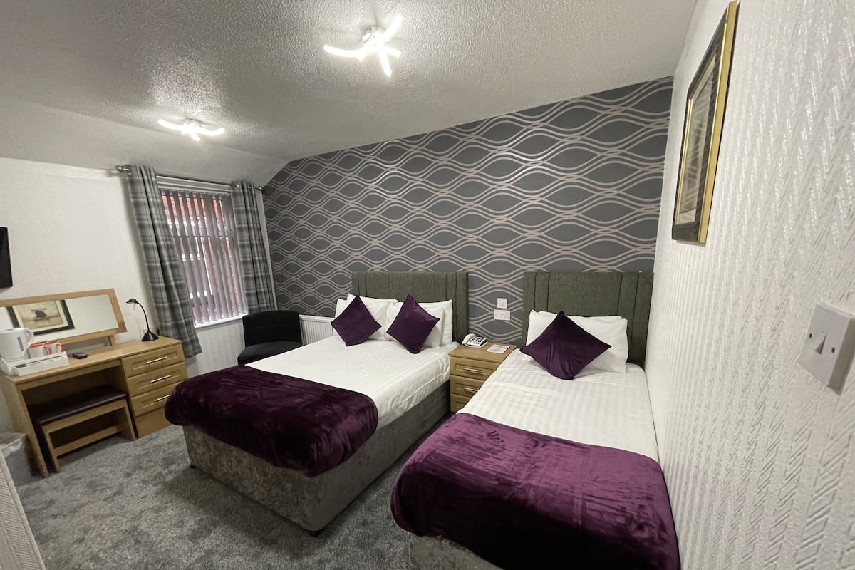 A room with two beds, a desk, and a chair.