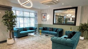 A modern living room with teal sofas, a glass coffee table, and potted plants. - Ruskin Hotel (Blackpool)