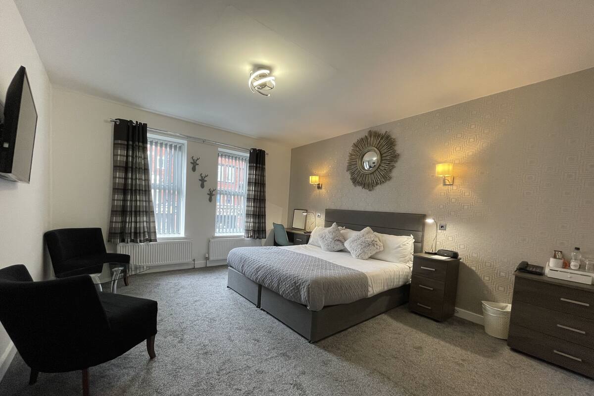 A modern bedroom with a large bed, two bedside tables, a chair, and a radiator.