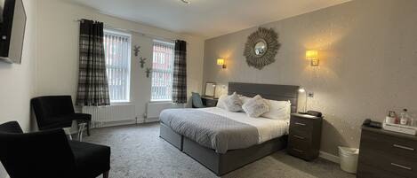 A modern bedroom with a large bed, two bedside tables, a chair, and a radiator.