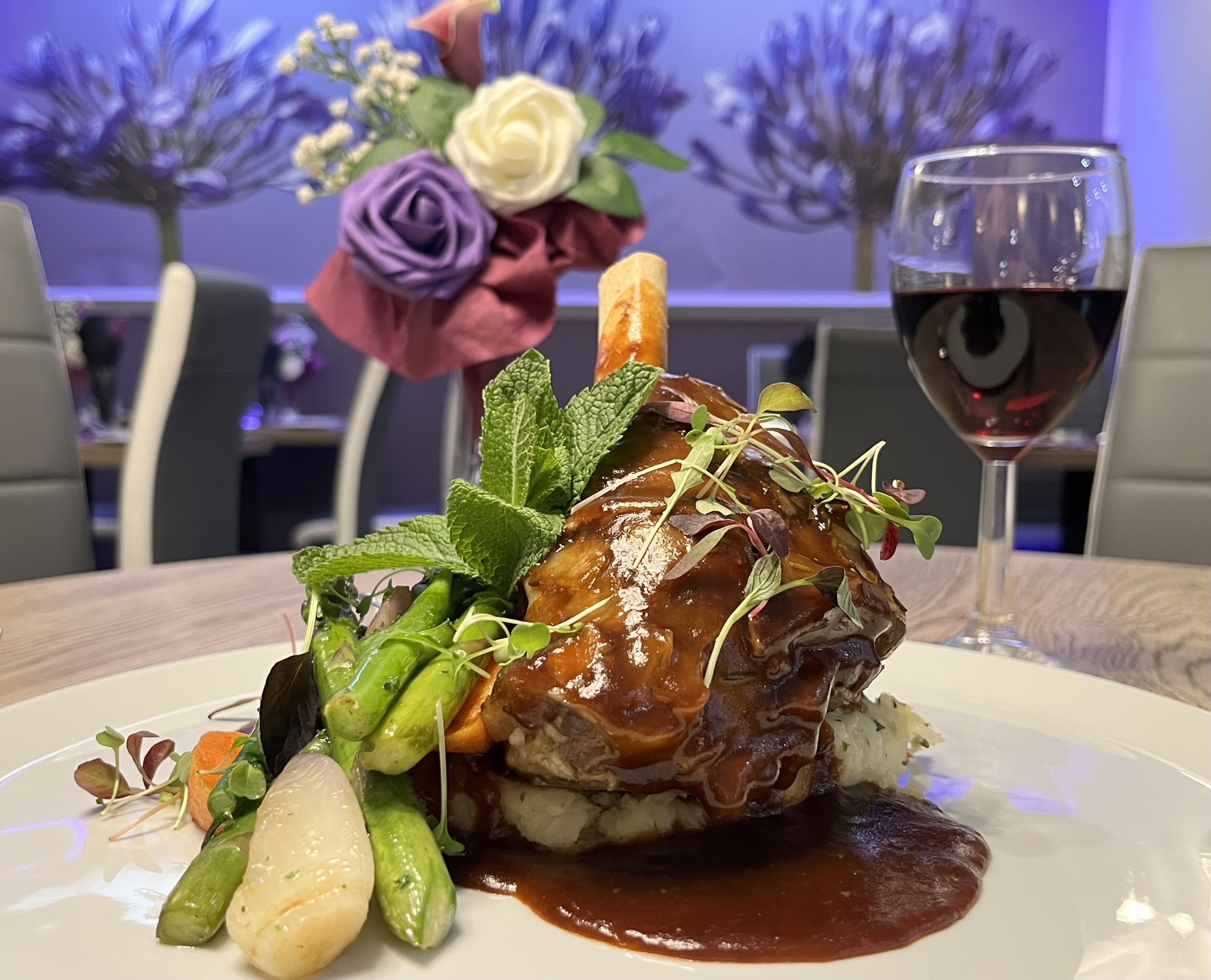 Un plato con carne, verduras y una copa de vino tinto.