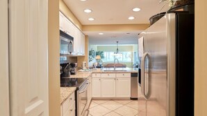 Una cocina moderna con armarios blancos, un refrigerador de acero inoxidable y un microondas.