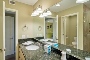 A modern bathroom with a large mirror, a granite countertop, a sink, and a shower area. - Sunswept at Hilton Head Island 2 Bedroom Holiday Home (Hilton Head Island)