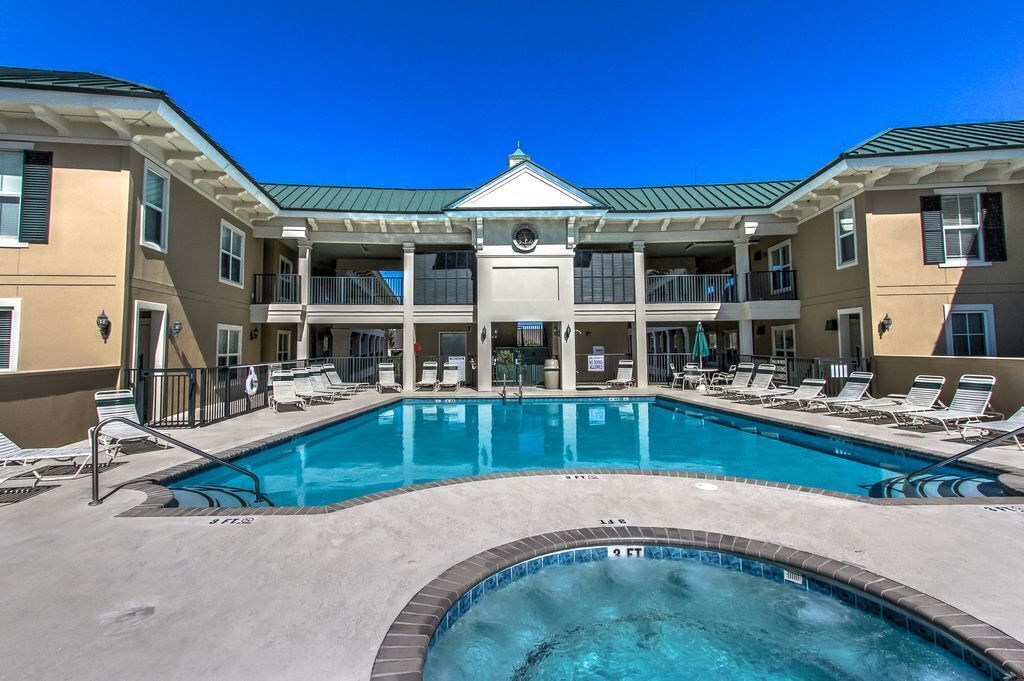 A hotel with a central pool, multiple balconies, and a two-story building.
