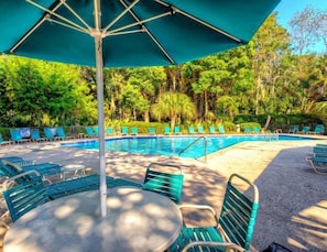 A pool area with lounge chairs and umbrellas, surrounded by lush greenery. - Vista Verde 2 Bedroom Holiday Home (Hilton Head Island)