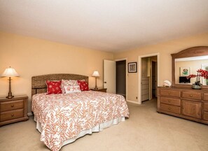 A bedroom with a bed, nightstands, a dresser, and a mirror.