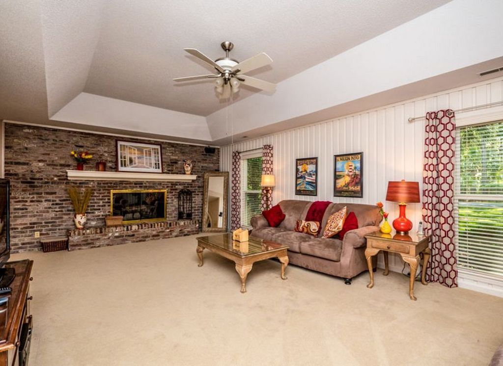 A living room with a fireplace, a ceiling fan, a sofa, and a coffee table.