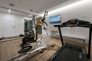 Une salle de sport équipée d’appareils de cardio, notamment un tapis de course, un vélo d’appartement et un appareil elliptique.