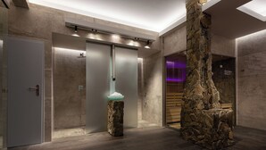 Une salle de bain moderne avec une colonne en pierre, une porte en verre dépoli et un luminaire.