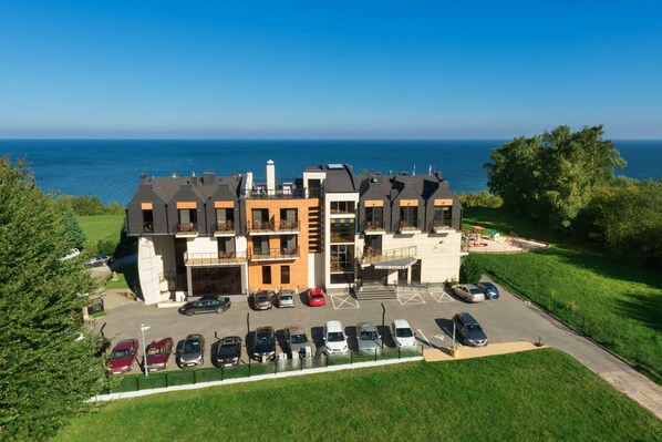 Un hôtel à plusieurs étages avec un parking situé devant, donnant sur une étendue d’eau.