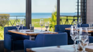 Un restaurant avec des tables et des chaises, une vue sur la mer et une rambarde.