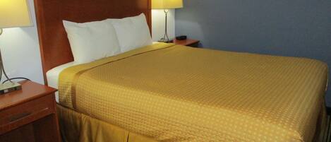 A hotel room with a large bed, two bedside lamps, a wooden nightstand, and a framed picture on the wall.