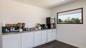A kitchen with white cabinets, a granite countertop, and various kitchen appliances and items. - Travelodge by Wyndham Spirit Lake/Okoboji (Spirit Lake)
