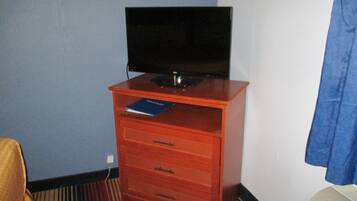 A small room with a wooden cabinet containing a television, a book, and a white air conditioner.