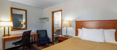A hotel room with a bed, desk, chair, and a mirror.