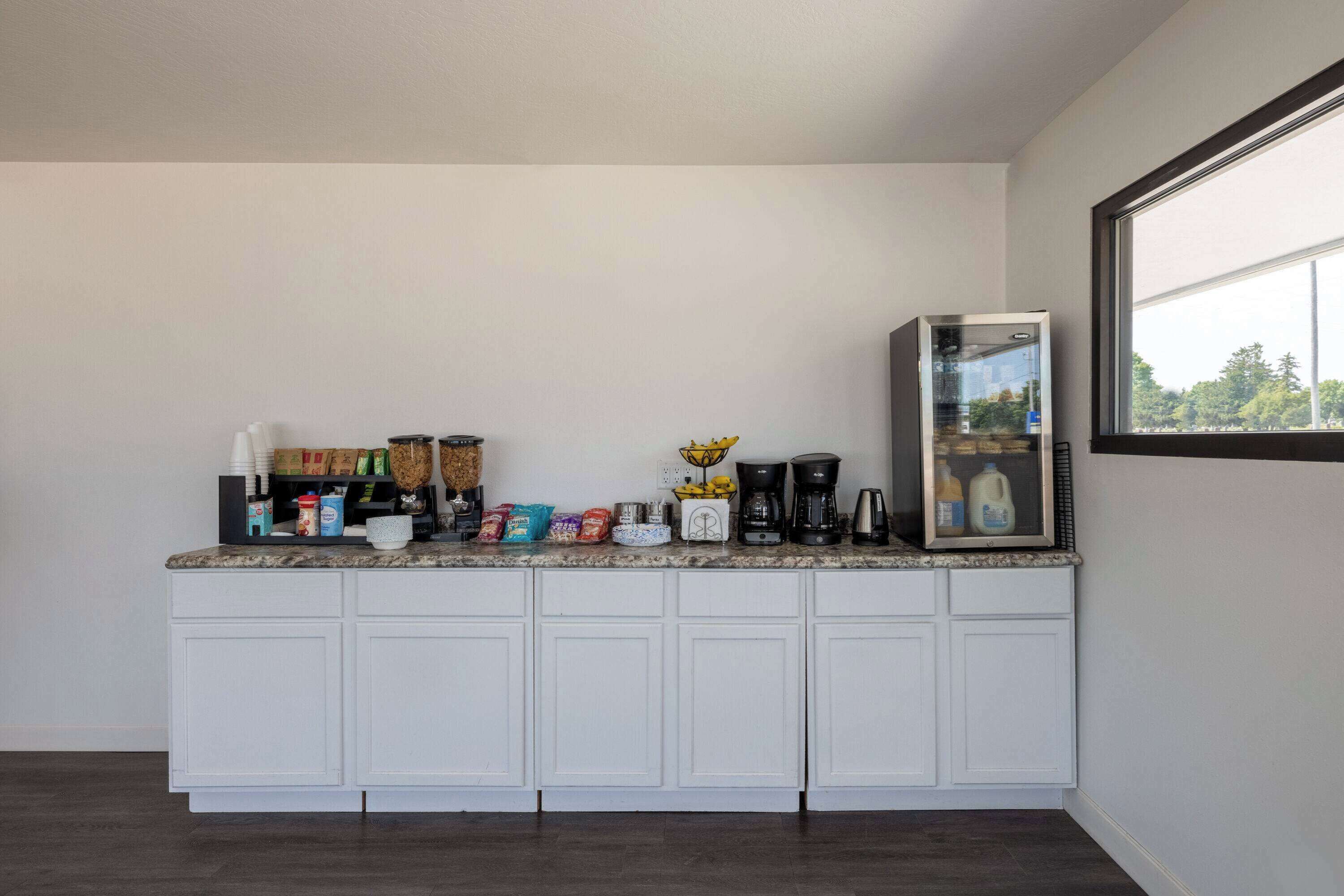 A kitchen with white cabinets, a countertop with various items, a coffee maker, and a refrigerator.
