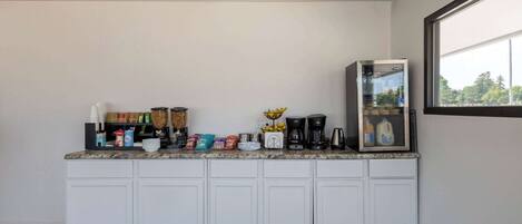 A kitchen with white cabinets, a countertop with various items, a coffee maker, and a refrigerator.