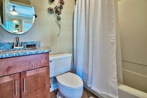 Un baño con inodoro, lavamanos, espejo y cortina de ducha.
