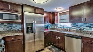 A modern kitchen with stainless steel appliances, dark wood cabinets, and a patterned backsplash. - 20 Sanddollar 3 Bedroom Holiday Home by Five Star Properties (Miramar Beach)