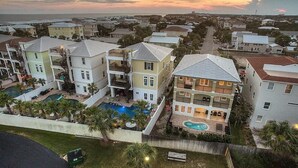 A residential area with multiple two-story houses, a swimming pool, and a view of the ocean at sunset. - Acqualina 9 Bedroom Holiday Home by Five Star Properties (Miramar Beach)