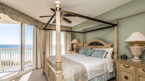 Un lit à baldaquin avec vue sur le balcon, une table de chevet avec une lampe et une commode avec des tiroirs.