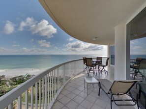 A balcony with a view of the beach and ocean.