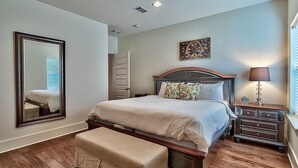 Ein Schlafzimmer mit einem großen Bett, einem Nachttisch, einer Bank, einem Spiegel und einem Wandbild.