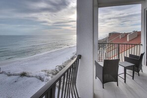 A balcony with a view of a snowy beach and ocean.