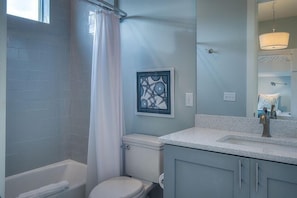 A bathroom with a bathtub, toilet, and a sink with a mirror above it.