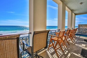 A covered outdoor seating area with wicker chairs and a pool table, overlooking a beach with clear blue water. - Bella Beach 5 Bedroom Holiday Home by Five Star Properties (Miramar Beach)