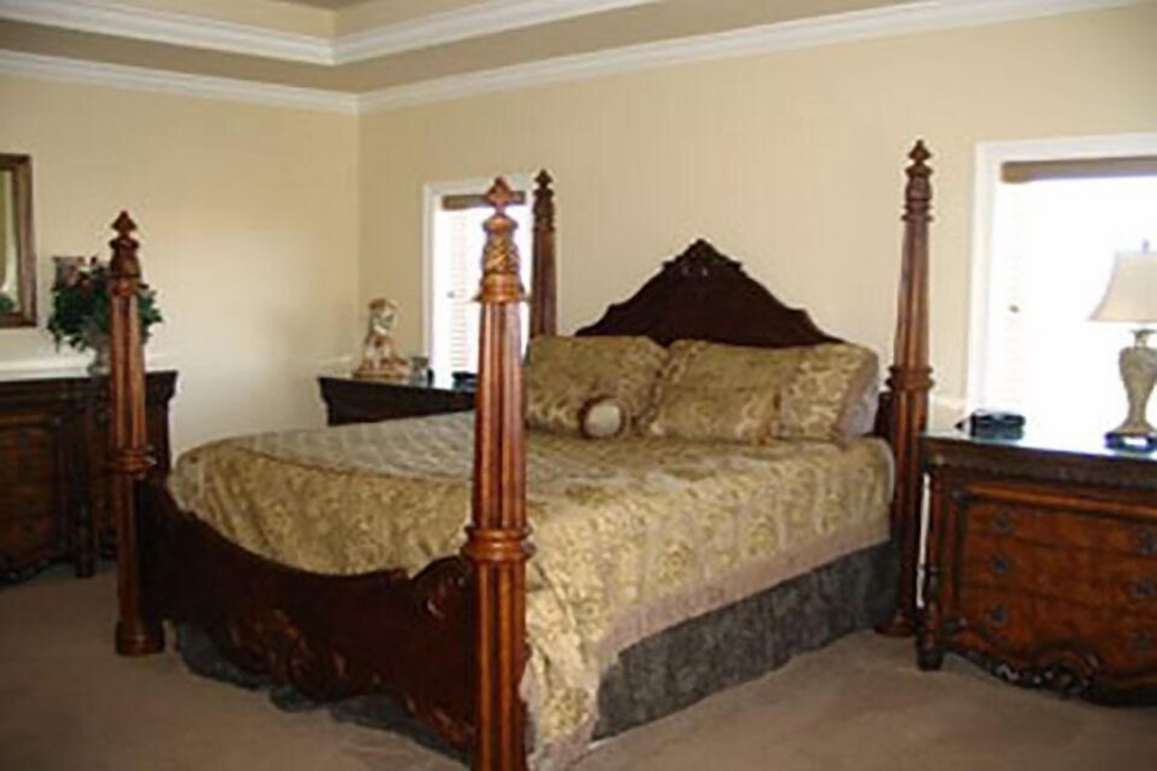 A four-poster bed with a wooden frame and a quilted bedspread.