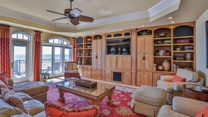 A spacious living room with a large wooden cabinet, a ceiling fan, and a view to the outside. - Bella Luna 4 Bedroom Holiday Home by Five Star Properties (Destin)