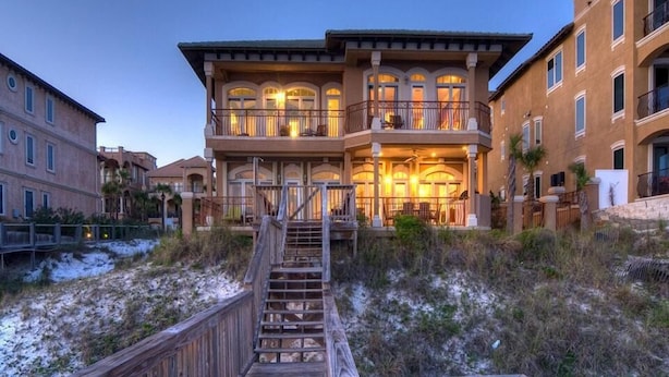 A multi-story building with a wooden deck leading to a balcony, surrounded by sand dunes. - Bella Luna 4 Bedroom Holiday Home by Five Star Properties (Destin)