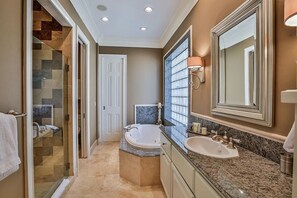Une salle de bain avec une baignoire, deux lavabos, un grand miroir et une cabine de douche en verre.