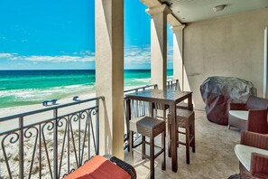 A balcony with a view of the ocean, equipped with wicker furniture and a barbecue grill. - Bella Vizio 5 Bedroom Holiday Home by Five Star Properties (Miramar Beach)