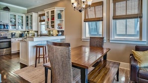 A modern kitchen with white cabinetry, a wooden dining table, and a chandelier. - Bella Vizio 5 Bedroom Holiday Home by Five Star Properties (Miramar Beach)