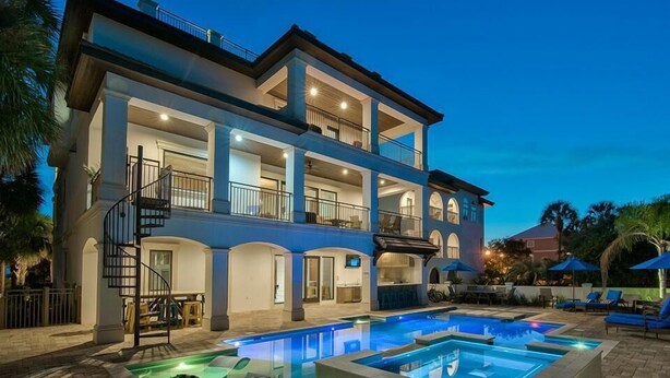 A multi-story building with a pool area, including a hot tub and lounge chairs.