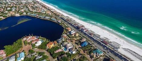 An aerial view of a coastal residential area with a beach, a marina, and a large body of water.