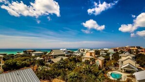 A coastal residential area with houses, a swimming pool, and a view of the ocean.