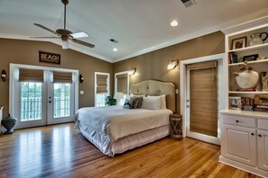 A bedroom with a large bed, a ceiling fan, and a bookshelf.