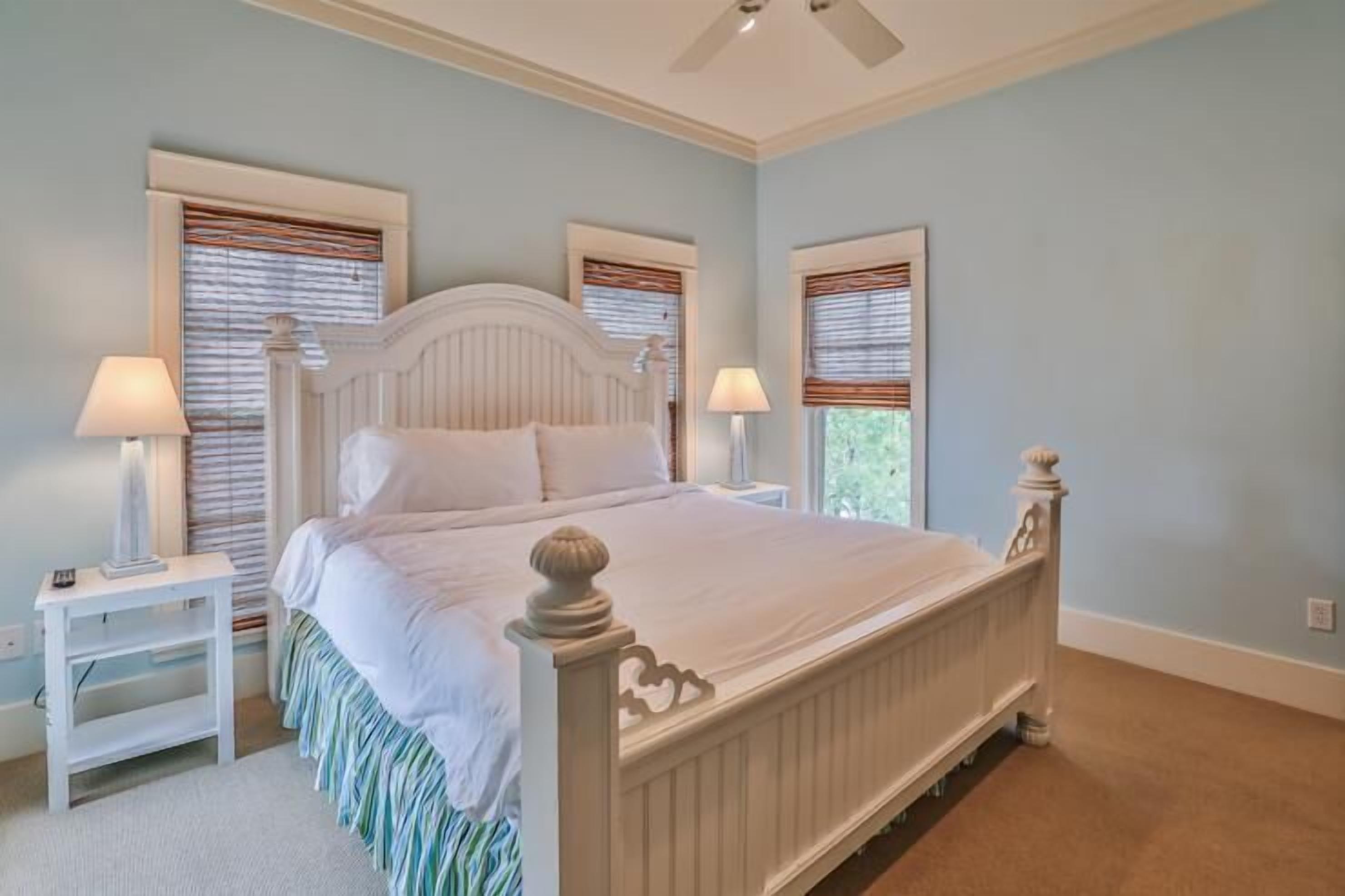 A bedroom with a white bed, two nightstands, and a ceiling fan.
