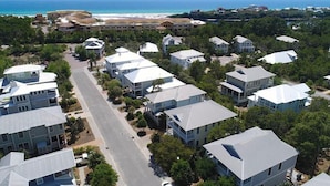 Un quartier résidentiel en bord de mer, avec des maisons dotées de toits à pignons, entourées de verdure et avec une plage en arrière-plan.